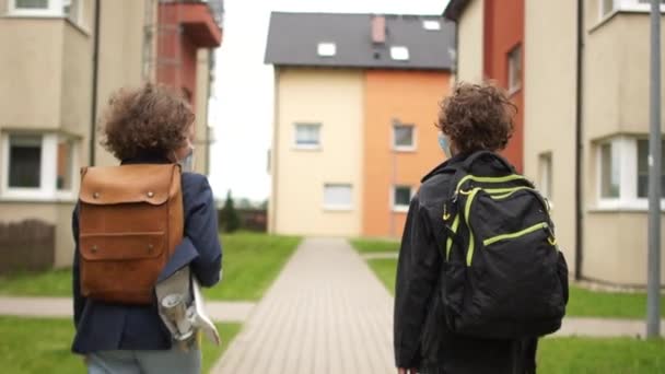 Ritorno a scuola distanza sociale. Due scolari, un ragazzo e una ragazza, si salutano toccandosi i gomiti. Torniamo a scuola dopo l'isolamento. Vita post-quarantena — Video Stock