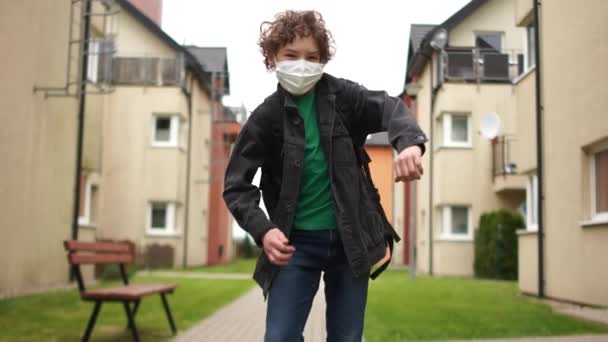 Le portrait rapproché d'un écolier masqué avec un sac à dos revient de l "école et danse. Danse folle, fin de la quarantaine, vie post-quarantaine — Video