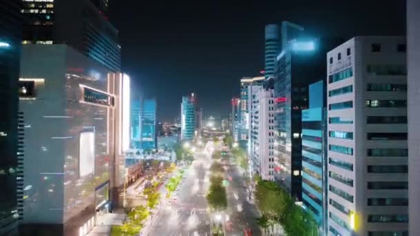 夜のソウル江南地区の美しい空中高波 道路交通の輝く光を示す高速道路の上の近代的な高層ビルの間を移動するカメラ — ストック動画