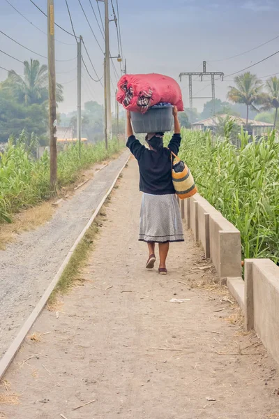 Una mujer con una cesta en la cabeza camina por un pueblito de Guat —  Fotos de Stock
