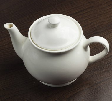 Bir beyaz demlik ve fincan tabağı ahşap tablo