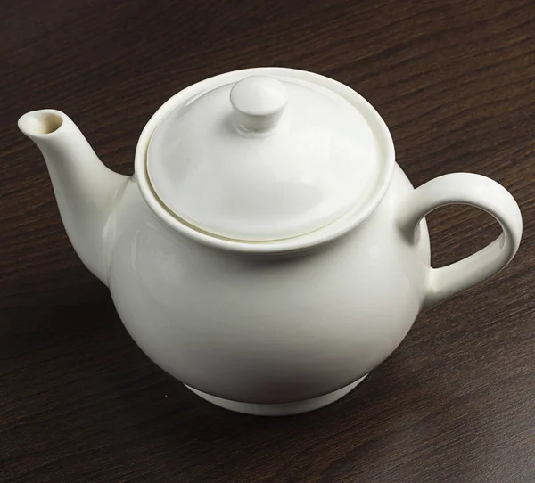 One white teapot and the saucer on the wooden table — Stock Photo, Image