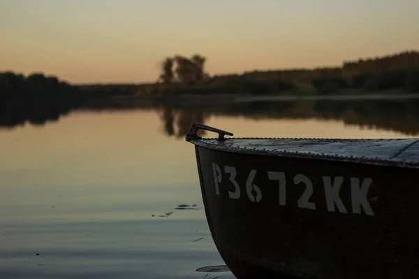 En vacker gyllene solnedgång vid floden. Älskare rida i en båt på en sjö under en vacker solnedgång. Lyckligt par kvinna och man tillsammans avkopplande på vattnet. Den vackra naturen runt. — Stockfoto