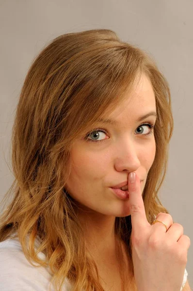 在她的嘴前的一个手指手势的年轻女子的肖像 — 图库照片
