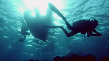 Tüplü dalgıçlar siluetleri kauçuk tekne altında