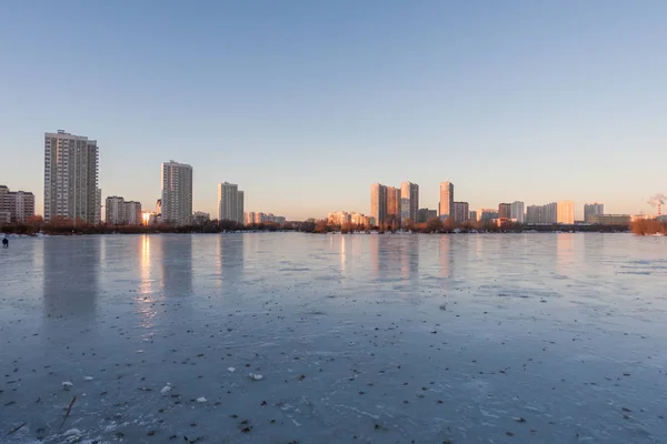 Frozen lake reflecting buildings and sky