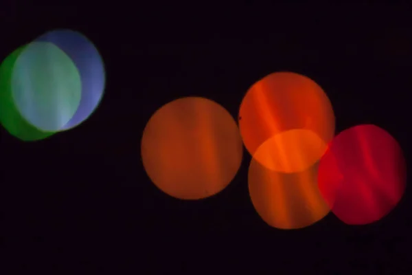 Colorful abstract blurry defocused bokeh lights on black background. Green, orange, blue and red spots — Stock Photo, Image