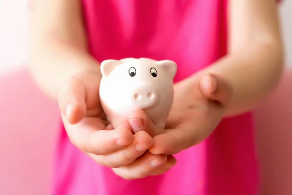 Pink piggy bank on children hands. Close up, selective focus. — Stock Photo, Image