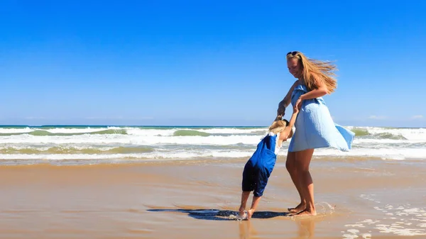 母と娘は晴れた日にビーチで回転しています. — ストック写真