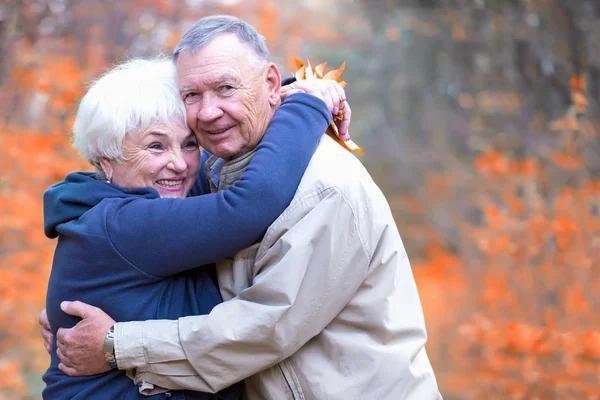 Homem e mulher idosos abraçando em um parque de outono — Fotografia de Stock