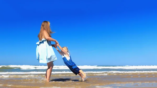 Matka a dcera se točí na pláži. — Stock fotografie