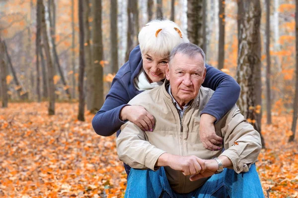 Feliz casal sênior sentado e sorrindo em um outono parque — Fotografia de Stock