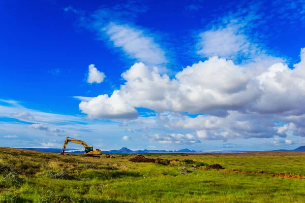 Excavadora en el campo bajo el cielo azul —  Fotos de Stock