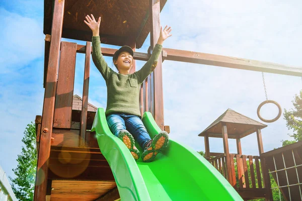 Impavida bambina che scivola sul parco giochi da sola nel tempo soleggiato — Foto Stock