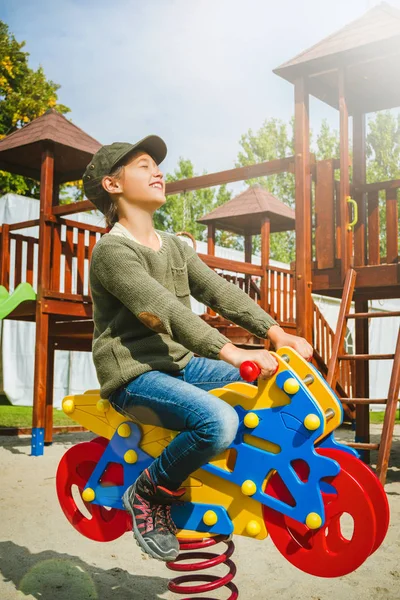 Lycklig liten flicka rider motorcykel på lekplatsen ensamma i soligt väder — Stockfoto