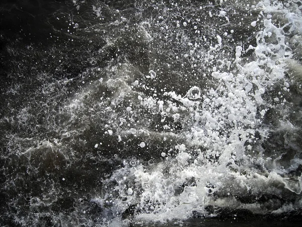 海水的黑浪拍打着海岸的岩石 无数的飞溅 水滴和白沫散落 — 图库照片