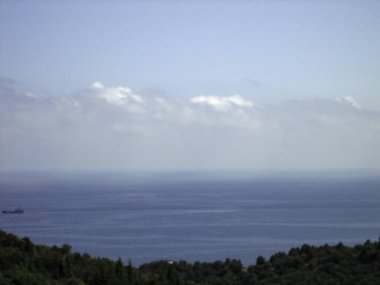 Kıyı dağlarından deniz manzarası. Kıyı tepeleri yoğun bitki örtüsüyle çevrilidir..