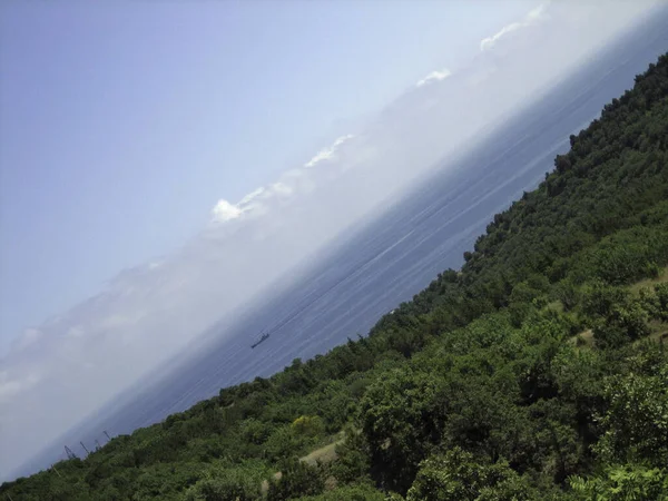 Sea view from the coastal mountains. The coastal hills are surrounded by dense vegetation.