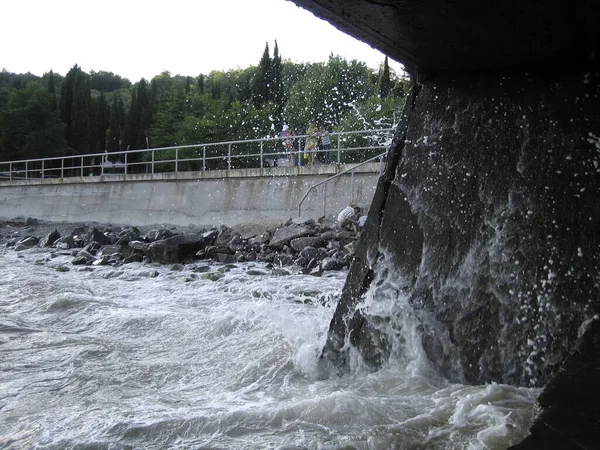 Tengervíz Fröccsenése Kőmóló Alatt Sok Habbal Permetezéssel Egy Zsindelyes Strand — Stock Fotó