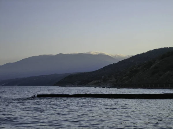 Rompeolas Orilla Mar Tranquilo Sobre Fondo Las Montañas Costeras Neblina — Foto de Stock