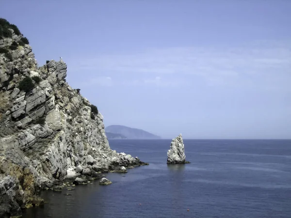 阳光明媚的日子里 高高的岩石群山耸立在一个风景如画的海湾蓝色的水面之上 — 图库照片