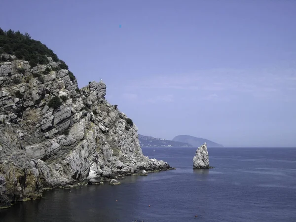 阳光明媚的日子里 高高的岩石群山耸立在一个风景如画的海湾蓝色的水面之上 — 图库照片