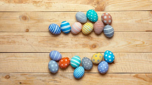 Coloridos huevos de pascua handamde sobre fondo de tablero de madera con espacio. Estilo laico plano — Foto de Stock