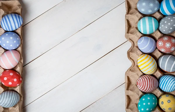 Dos bandejas con huevos de Pascua coloreados, pintados a mano, se encuentran una enfrente de la otra sobre un fondo de madera situado en diagonal. Plano — Foto de Stock