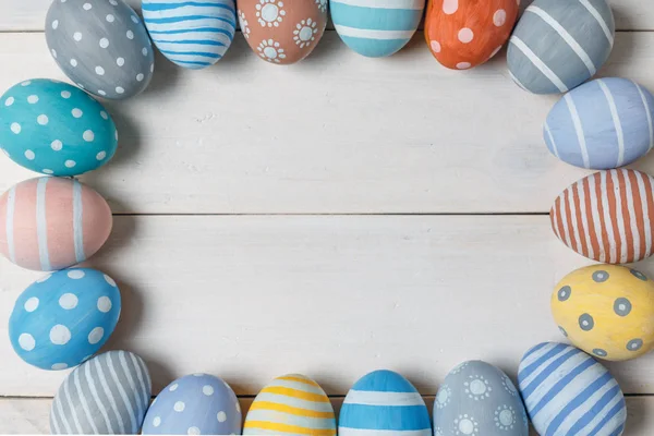 Elipse de coloridos huevos de Pascua sobre un fondo de madera blanca de cerca, vista superior — Foto de Stock