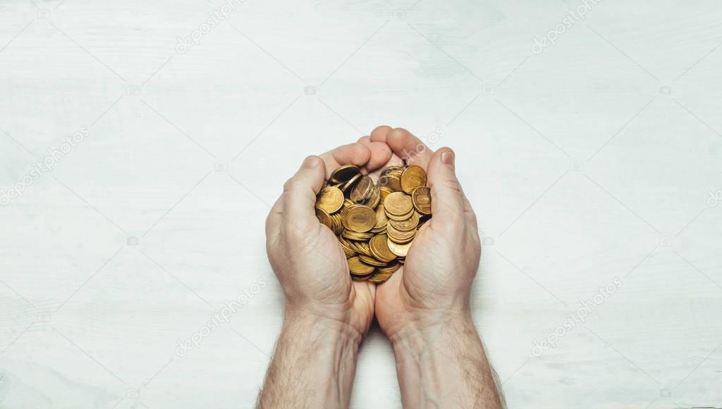 Male hands with a handful of coins in the palms on a light white background. Flat style