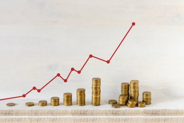 Altın sikke yığınları ahşap arka plan üzerinde kırmızı ok ile bir grafik düzenlenmiştir. Ticari büyüme ve para kavramı kaydetme