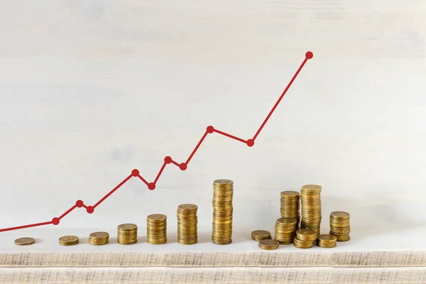 Altın sikke yığınları ahşap arka plan üzerinde kırmızı ok ile bir grafik düzenlenmiştir. Ticari büyüme ve para kavramı kaydetme