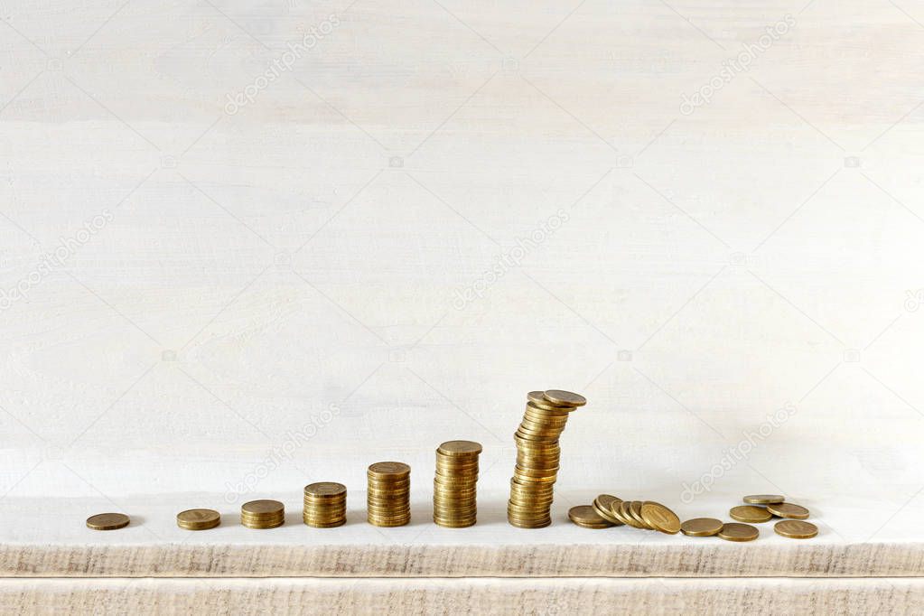 Growing coins columns, the biggest one is falling, all on wooden background. Do not keep all your eggs in one basket