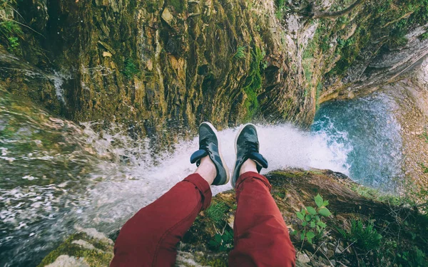 Pár férfi lábát a rock a vízesés háttér — Stock Fotó