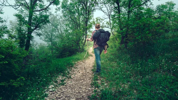 Άνθρωπος ταξιδιώτης περπατά κατά μήκος ένα μονοπάτι μέσα από ένα ορεινό δάσος. Ταξίδια ζωής — Φωτογραφία Αρχείου