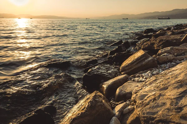 Taş deniz kıyısında günbatımı güneşli yaz plaj rahatlatıcı kavramı Gelendzhik arka plan
