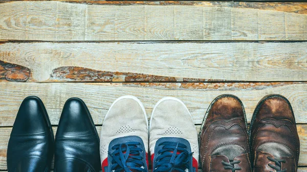Tres pares de zapatos en respaldo de madera: zapatos Busines, zapatos casuales y botas de senderismo Concepto de elegir el calzado adecuado — Foto de Stock