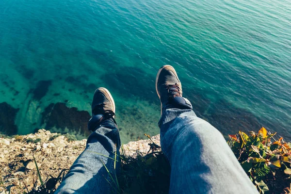 Mens ben i sneakers i bakgrunden av pittoreska havet landscapehiking resa avkopplande koncept — Stockfoto