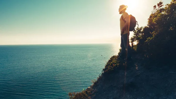 Hombre viajero se para en la parte superior y disfruta del paisaje marino durante la puesta del sol — Foto de Stock