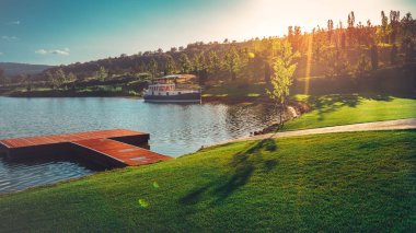 Bir iskele ve zemin Hills ve güneş eğlence eğlence kavramı karşı bir gemi ile pitoresk göl