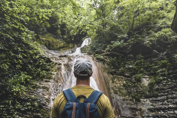 El viajero ha llegado al destino y disfrutando de la vista de la cascada y la belleza de la naturaleza virgen. Contemplación Aventura Concepto — Foto de Stock