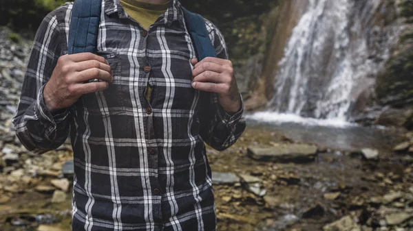 Manos irreconocibles del hombre sostiene una correa de la mochila en el fondo de la cascada Viaje de senderismo Viaje Trek Concepto — Foto de Stock