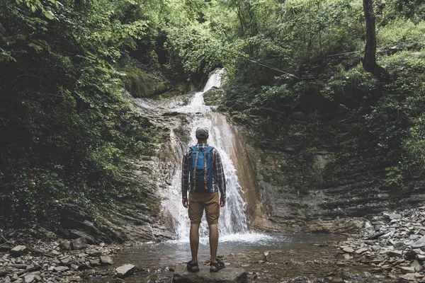 El viajero alcanzó el destino y disfruta de la vista de la cascada, el concepto de aventura de contemplación posterior — Foto de Stock