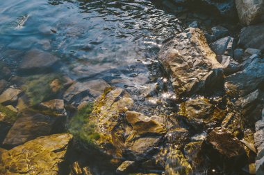 Pitoresk taş sahil, su güneş ışınlarının yansıması. Rekreasyon boş zaman yolculuğu kavramı