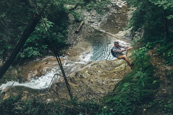 Climber erkeği tepenin şelale arka plan Hiking dağ macera kavramı üzerinde tırmanıyor. — Stok fotoğraf