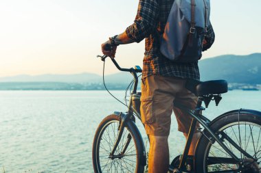 Sahil bisiklet ile ayakta ve doğa günbatımı tatil kavramı dinlenme gevşeme seyahat manzarayı tanınmaz seyahat adam