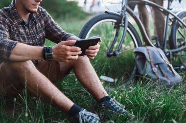 Yaz Çayır yakınındaki tutarak ve Tablet rekreasyon seyahat hedef kavramı dinlenme seyir bisiklet, tanınmayan genç yolcusu adam oturur