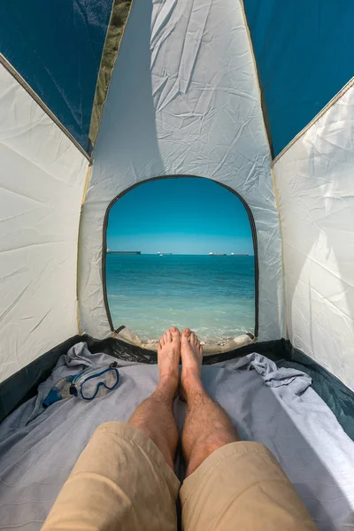 Tourist Man Lying In Tent With A View Of  Sea Summer Beach Holiday Vacation Concept. View Of Legs. Point Of View Shot — Stock Photo, Image