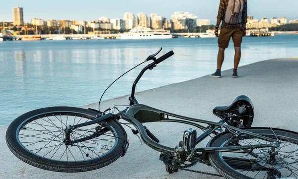 Bicicleta se encuentra en el muelle junto a un joven disfruta de la vista de la naturaleza, Vista trasera — Foto de Stock