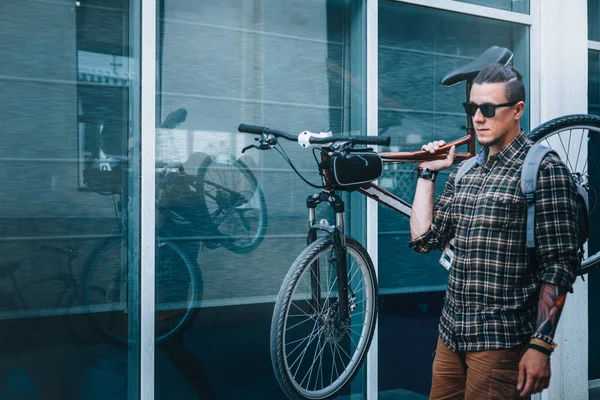 Guapo joven con gafas lleva bicicleta en su hombro — Foto de Stock